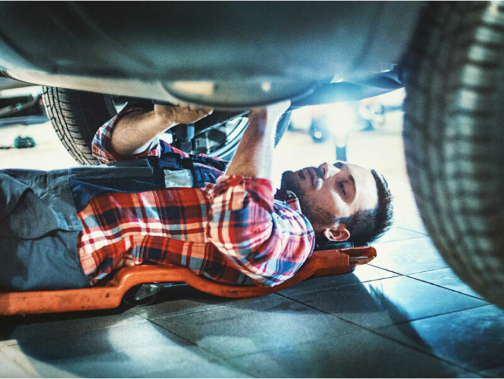 Autoreparatur Ein Mann liegt unter einem Auto und arbeitet