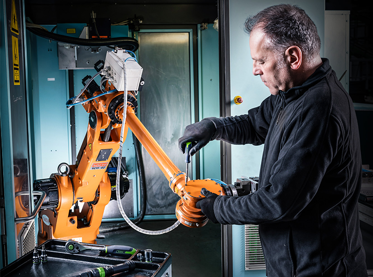 Ein Mann repariert einen Roboter Arm mit Kukko Werkzeug